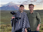 Two guys holding a camera stand in front of a volcano in Ecuador